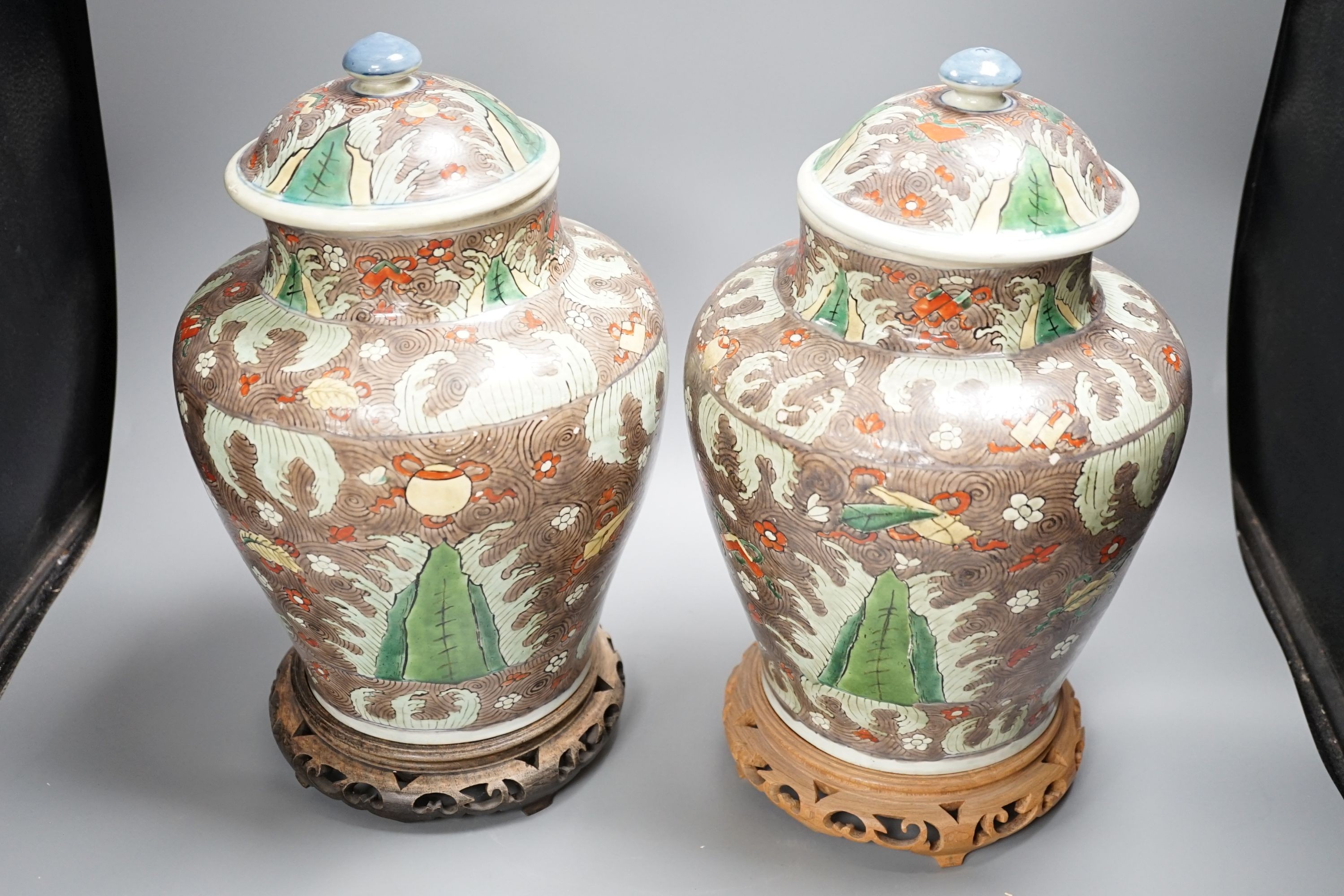 A pair of Chinese enamelled porcelain jars and covers, in Transitional style, 34cm high, wood stands